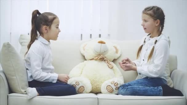 Two pretty girls sitting on the sofa, playing rock-paper-scissors to decide who will play with white soft bear. - Footage, Video