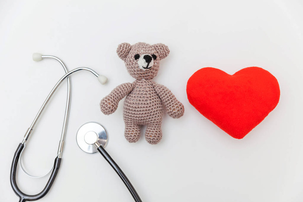 Semplicemente minimale giocattolo di design orso cuore rosso e attrezzature mediche stetoscopio isolato su sfondo bianco. Concetto medico di assistenza sanitaria bambini. Simbolo pediatrico. Layout piatto, vista dall'alto copia spazio
 - Foto, immagini