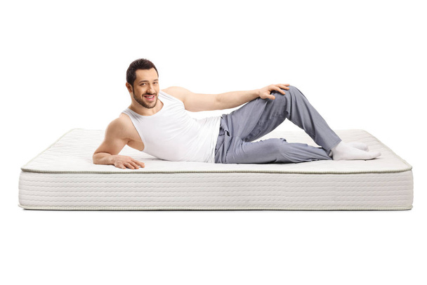 Young handsome man lying on a bed mattress - Fotoğraf, Görsel