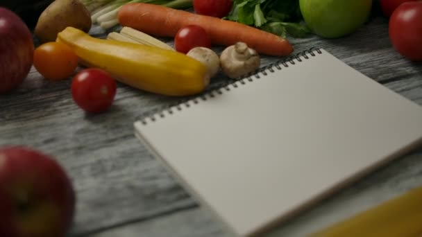 Cuaderno en blanco cerca de los ingredientes de cocina en la mesa de madera - Metraje, vídeo