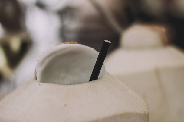 Bílá kokosová voda na stole s černou slámou - Fotografie, Obrázek