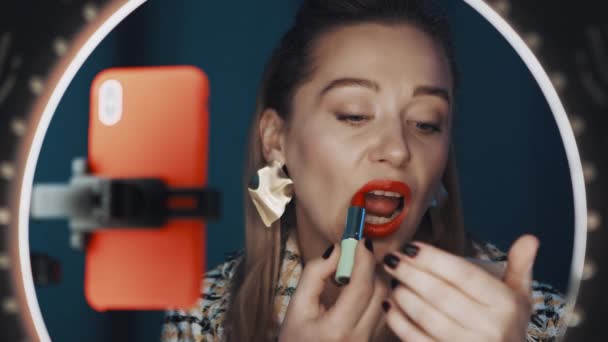 Belle femme blogueur de mode applique rouge à lèvres devant la lumière anneau en ligne
. - Séquence, vidéo