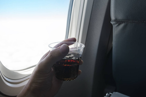 Holding a glass of soda on a plane - Φωτογραφία, εικόνα