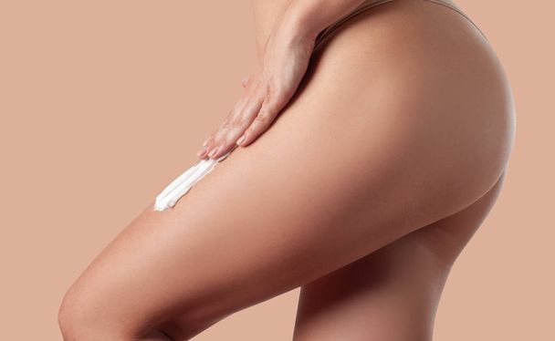 Cuidado corporal. Mujer aplicando crema contra la celulitis en las piernas
. - Foto, Imagen