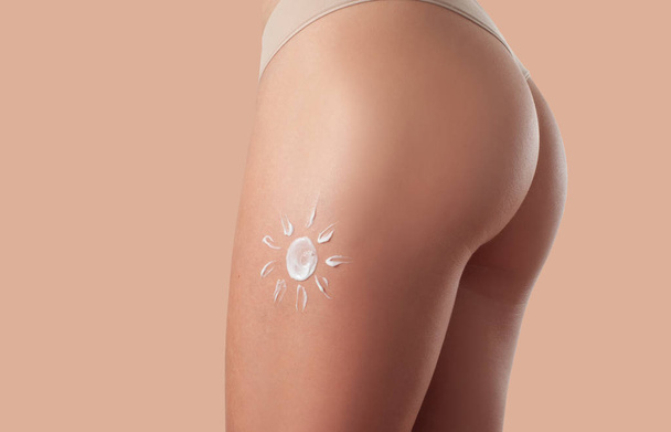Body care. Woman applying sunscreen lotion on legs and buttocks. - Foto, afbeelding