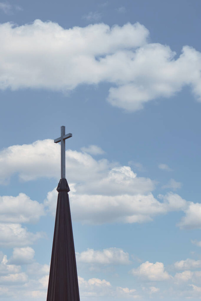雲に覆われた空を背景に教会の尖塔の上を横切り - 写真・画像