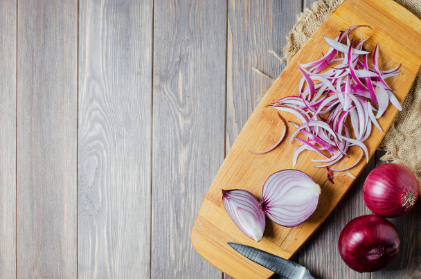 Red onion sliced. The process of cooking on a yellow cutting Board. Flat top view - Фото, изображение
