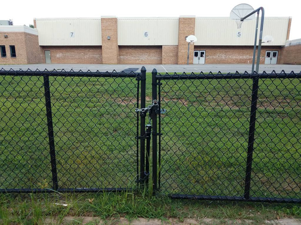 закрытые ворота и баскетбольная площадка и здание школы
 - Фото, изображение