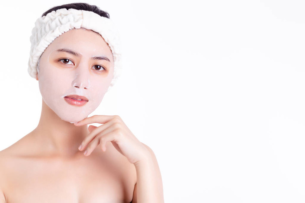 Jovem mulher asiática em colágeno rosto máscara folha que fazem agradável pele facial radiante. conceito de cuidados da pele. Uma jovem bonita mostra uma pele clara e brilhante. Rapariga linda. espaço de cópia, isolado no branco
 - Foto, Imagem