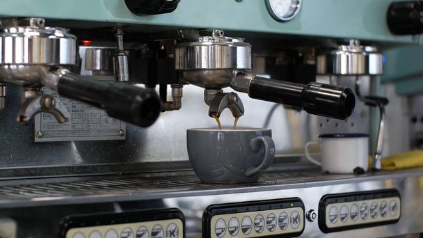 Barista bei der Arbeit. der Prozess der Kaffee- und Kakaozubereitung. ein Glas schäumende Milch. Elektrische Mühle mahlt Kaffeebohnen in Filterhalter. - Foto, Bild