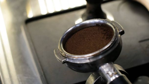 Barista at work. The process of making coffee and cacao. A glass of foaming milk. Electric Grinder Grinds Coffee Beans In Filter Holder. - Photo, Image