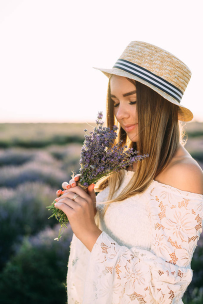The girl stands with a bouquet of lavender in the field and looks at it, close-up - Foto, Imagem