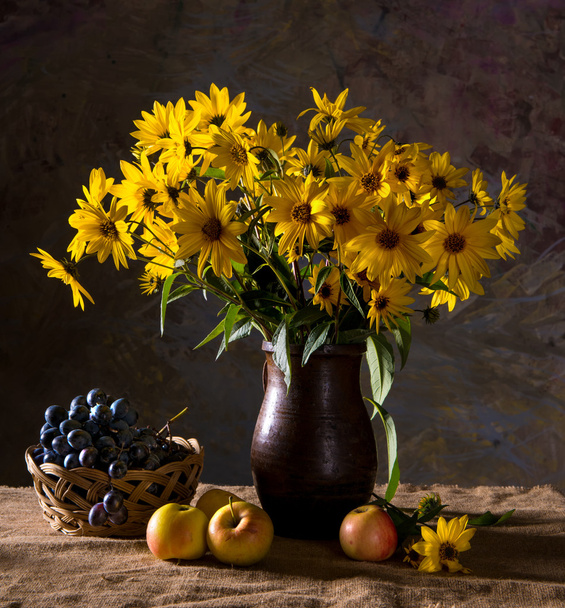Joukko keltaisia kukkia (rudbeckia) ruskea maljakko ja hedelmät
 - Valokuva, kuva
