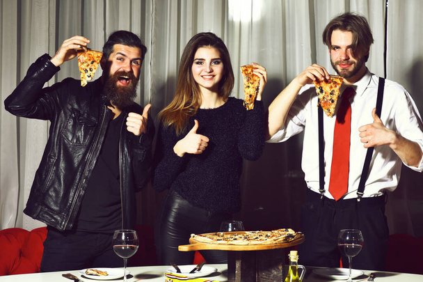 Happy friends eating tasty pizza slices with thumbs up gestures - Photo, Image