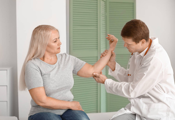 Arzt untersucht reife Frau mit Gelenkschmerzen in Klinik - Foto, Bild
