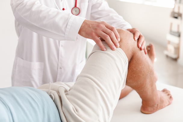 Doctor examining mature man with joint pain in clinic - Photo, Image