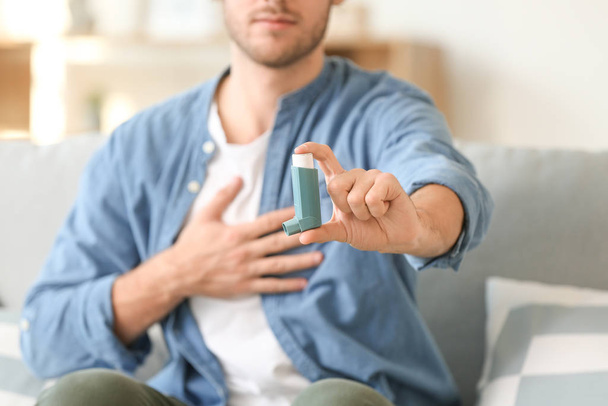 Sick man with asthma inhaler at home, closeup - Photo, Image