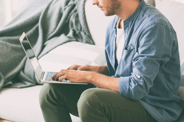 pohledný muž s laptop doma na pohovce - Fotografie, Obrázek