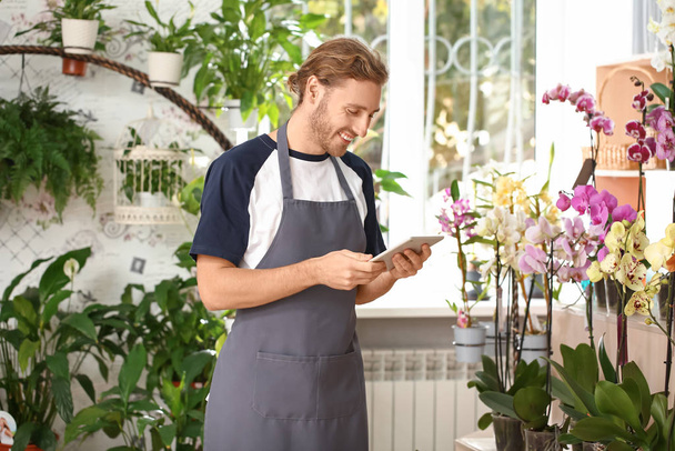 Male florist with tablet computer in shop - Foto, immagini
