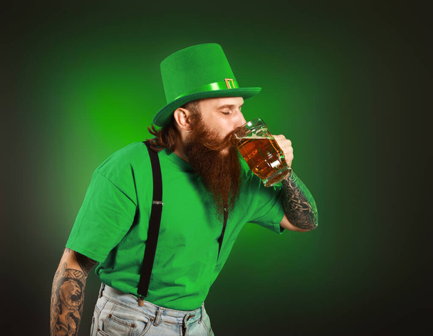 Homem barbudo com um copo de cerveja no fundo escuro. Celebração do Dia de São Patrício
 - Foto, Imagem