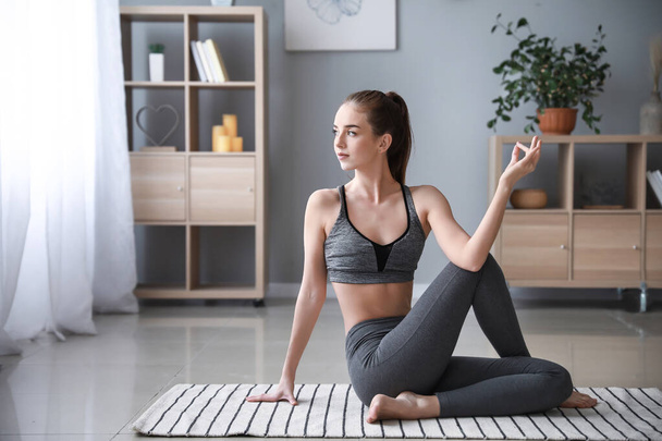 Schöne junge Frau praktiziert Yoga zu Hause - Foto, Bild