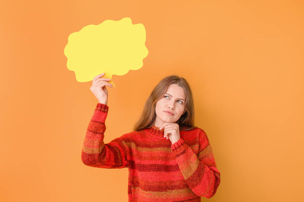 Thoughtful young woman with blank speech bubble on color background - Photo, Image