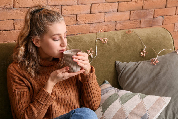Young woman in winter clothes drinking hot chocolate at home - Photo, image