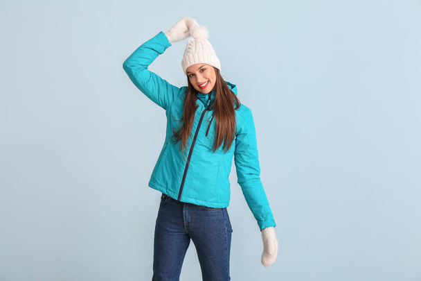 Ευτυχισμένη νεαρή γυναίκα σε χειμωνιάτικα ρούχα στο φόντο χρώμα - Φωτογραφία, εικόνα
