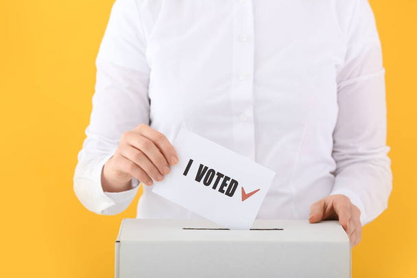 Ψηφοφορία γυναίκα κοντά σε κάλπη στο φόντο χρώμα - Φωτογραφία, εικόνα