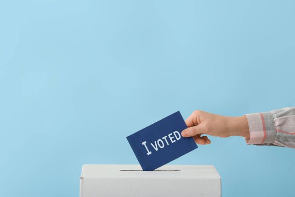 Ψηφοφορία γυναίκα κοντά σε κάλπη στο φόντο χρώμα - Φωτογραφία, εικόνα