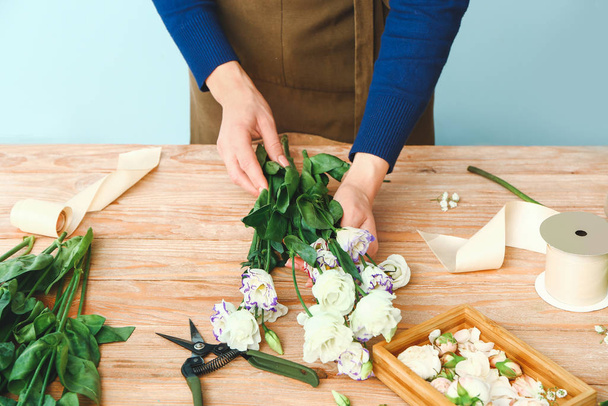 Female florist making beautiful bouquet at table - 写真・画像