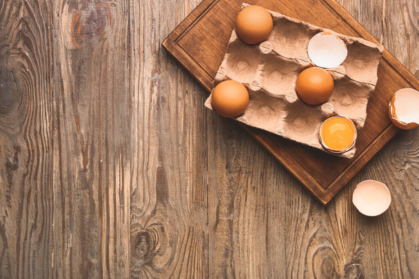 Package with fresh eggs on wooden table - Foto, imagen