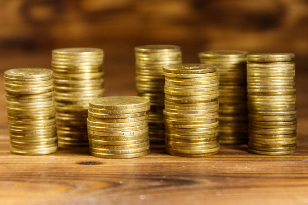 Stacks of golden coins on wooden background - Photo, Image