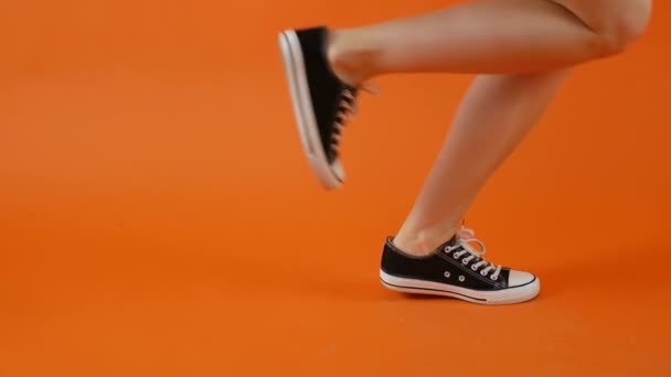 黒と白のスニーカーの女性の足は、スタジオで明るい背景で踊っています。古典的な靴健康的な生活、積極的な人々. - 映像、動画