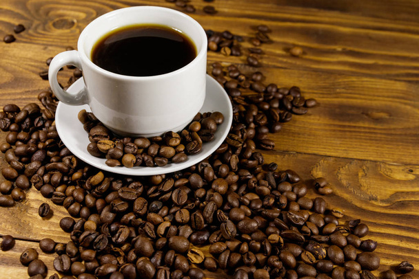 Xícara de café e grãos de café torrados em mesa de madeira
 - Foto, Imagem