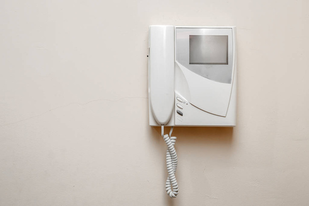 weiße Gegensprechanlage mit Bildschirm an beiger Wand - Foto, Bild