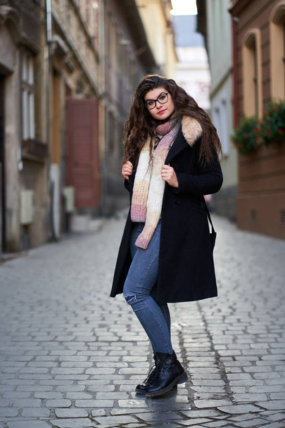 Young woman in black coat and blue jeans in an old town - Foto, immagini