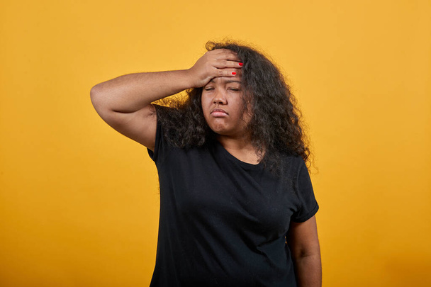 Mujer joven afroamericana cansada con sobrepeso manteniendo la mano en la frente
 - Foto, imagen