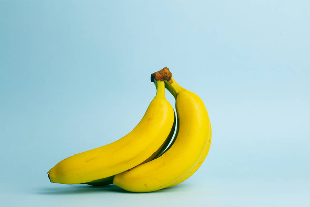Bananas on a blue pastel background. A branch of fresh bananas.  - Zdjęcie, obraz