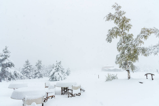 mesas y sillas de restaurante bajo una tormenta de nieve
 - Foto, Imagen