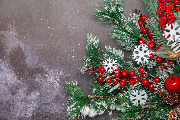 Christmas fir twigs with red berries and snowflakes on dark background - Фото, изображение