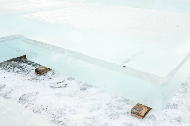 Ghiaccio tagliato in blocchi per la costruzione di una città di ghiaccio. Mattoni di ghiaccio si trovano su puntelli di legno
. - Foto, immagini