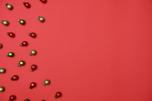 Creative Christmas pattern with red and green shiny baubles on red background - Foto, immagini