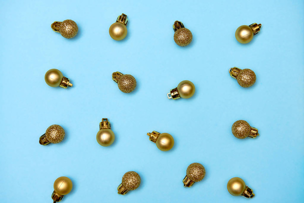 Creative Christmas pattern with golden shiny baubles on blue pastel background - Fotografie, Obrázek