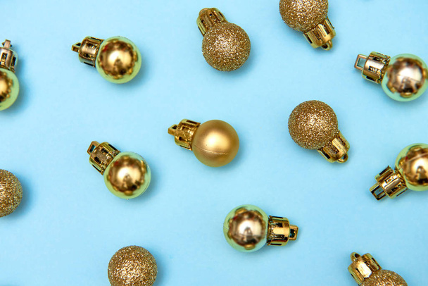 Creative Christmas pattern with golden shiny baubles on blue pastel background - 写真・画像