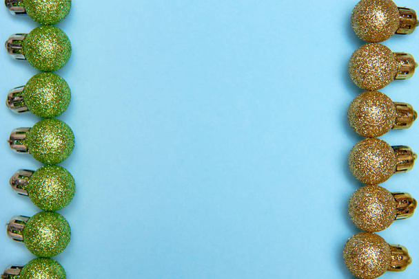 Patrón creativo de Navidad con adornos brillantes dorados y verdes sobre fondo azul pastel
 - Foto, Imagen