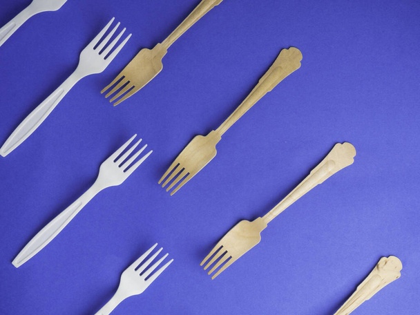 Fourchettes jetables en bambou biologique vs fourchettes en plastique sur fond bleu tendance. Fourchettes en bois et en plastique non-oragnique respectueuses de l'environnement
 - Photo, image