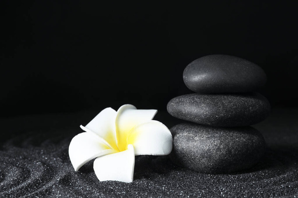 Spa stones and plumeria flower on black sand with beautiful pattern, space for text. Zen concept - Fotografie, Obrázek