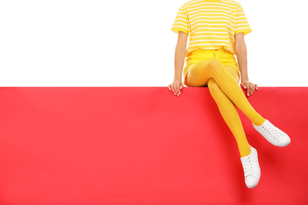 Woman wearing yellow tights sitting on color background, closeup - Valokuva, kuva