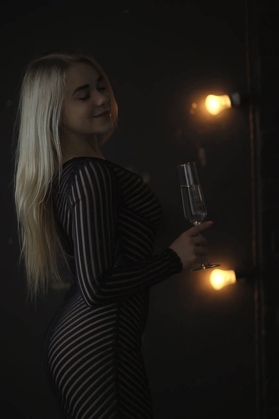 sexy blonde girl drinks champagne from a glass, evening glamorous style portrait - Фото, изображение
